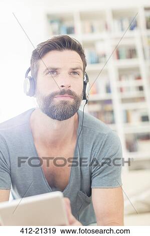 Stock Photo - Man listening to music in living room. Fotosearch