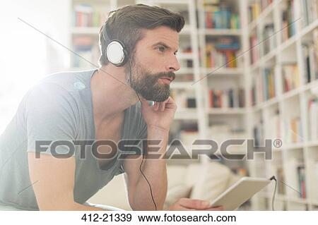 Stock Photo - Man listening to music in living room. Fotosearch