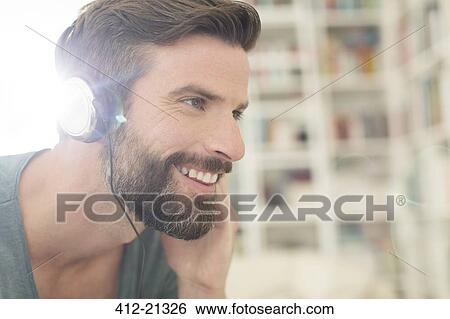 Man listening to music in living room View Large Photo Image Stock Photograph - Man listening to music in living room. Fotosearch