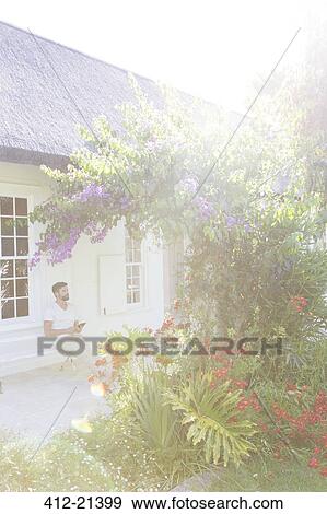 Man on porch admiring flowers in backyard View Large Photo Image Stock Photo - Man on porch admiring flowers in backyard. Fotosearch