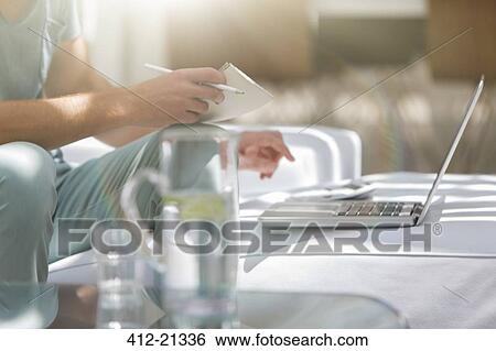 Man paying bills on laptop at coffee table View Large Photo Image Stock Photograph - Man paying bills on laptop at coffee table. Fotosearch