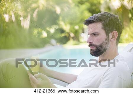 Man using digital tablet and drinking juice by swimming pool View Large Photo Image Stock Photography - Man using digital tablet and drinking juice by swimming pool. Fotosearch