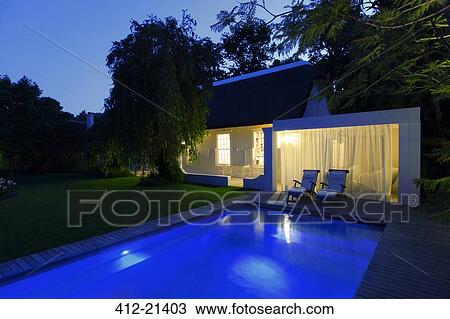 Modern house overlooking illuminated swimming pool at night View Large Photo Image Stock Image - Modern house overlooking illuminated swimming pool at night. Fotosearch