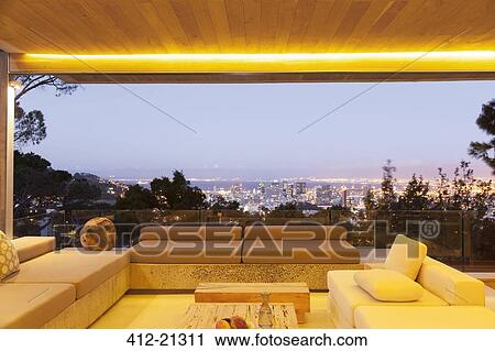 Modern living room overlooking illuminated cityscape at night View Large Photo Image Stock Image - Modern living room overlooking illuminated cityscape at night. Fotosearch