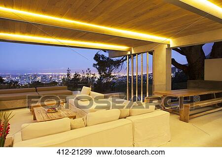 Stock Photo - Modern living room overlooking illuminated cityscape at night. Fotosearch