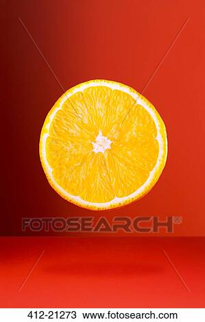 Stock Image - Orange slice on red counter. Fotosearch