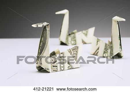 Stock Image - Origami swans made of dollar bills on counter. Fotosearch