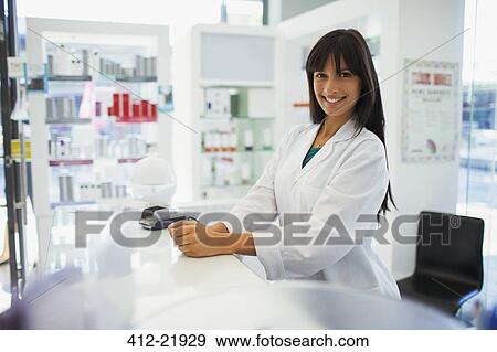 Stock Photo - Pharmacist smiling behind counter in drugstore. Fotosearch
