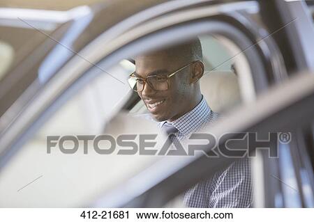 Smiling businessman sitting in car View Large Photo Image Stock Image - Smiling businessman sitting in car. Fotosearch