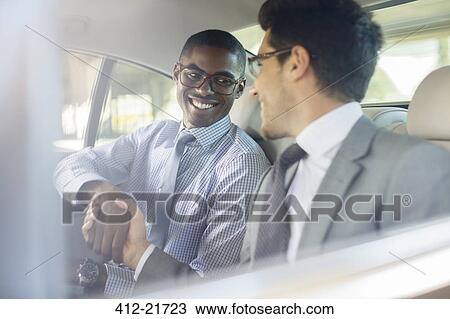 Smiling businessmen shaking hands in car View Large Photo Image Stock Image - Smiling businessmen shaking hands in car. Fotosearch