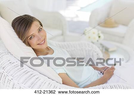 Smiling woman using cell phone in wicker chair View Large Photo Image Stock Image - Smiling woman using cell phone in wicker chair. Fotosearch