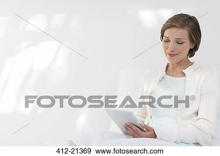 Stock Photo - Smiling woman using digital tablet. Fotosearch