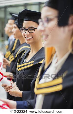 Student in cap and gown standing with colleges View Large Photo Image Picture - Student in cap and gown standing with colleges. Fotosearch