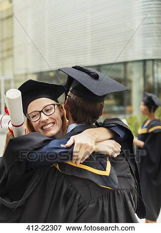 Stock Photo - Students in cap and gown hugging. Fotosearch
