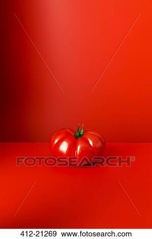 Tomato sitting on red counter View Large Photo Image Stock Photo - Tomato sitting on red counter. Fotosearch