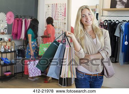 Stock Photo - Woman carrying shopping bags in clothing store. Fotosearch