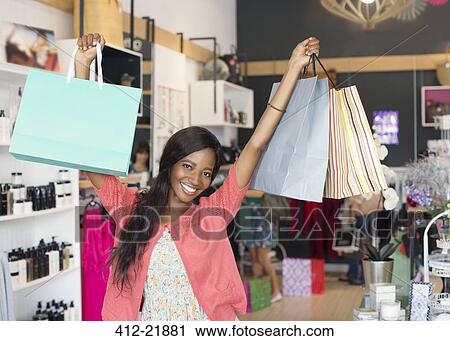 Stock Image - Woman carrying shopping bags in store. Fotosearch