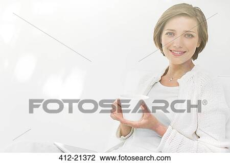 Stock Image - Woman drinking coffee and using digital tablet outdoors. Fotosearch