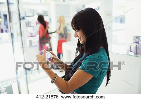 Woman examining perfume in drugstore View Large Photo Image Stock Photograph - Woman examining perfume in drugstore. Fotosearch