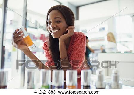 Woman examining skincare product in drugstore View Large Photo Image Stock Image - Woman examining skincare product in drugstore. Fotosearch