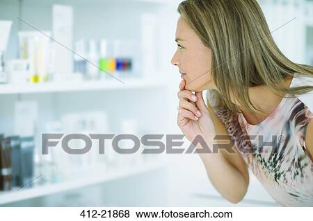 Woman examining skincare products in drugstore View Large Photo Image Stock Photo - Woman examining skincare products in drugstore. Fotosearch