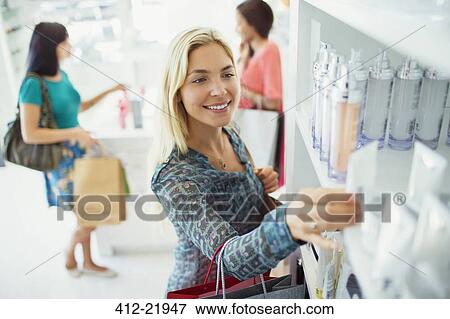 Woman examining skincare products in drugstore View Large Photo Image Stock Photo - Woman examining skincare products in drugstore. Fotosearch