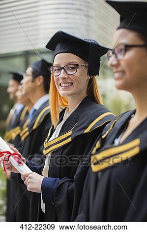 Woman in cap and gown standing with colleges View Large Photo Image Stock Photo - Woman in cap and gown standing with colleges . Fotosearch