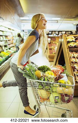 Woman playing on shopping cart in grocery store View Large Photo Image Stock Image - Woman playing on shopping cart in grocery store. Fotosearch
