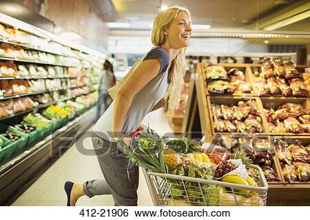 Woman playing with shopping cart in grocery store View Large Photo Image Stock Photograph - Woman playing with shopping cart in grocery store. Fotosearch