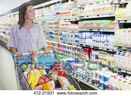 Woman pushing full shopping cart in grocery store View Large Photo Image Stock Image - Woman pushing full shopping cart in grocery store. Fotosearch