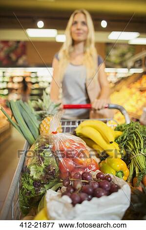 Woman pushing full shopping cart in grocery store View Large Photo Image Stock Photo - Woman pushing full shopping cart in grocery store. Fotosearch