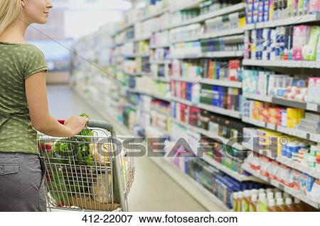Woman pushing full shopping cart in grocery store View Large Photo Image Stock Photo - Woman pushing full shopping cart in grocery store. Fotosearch