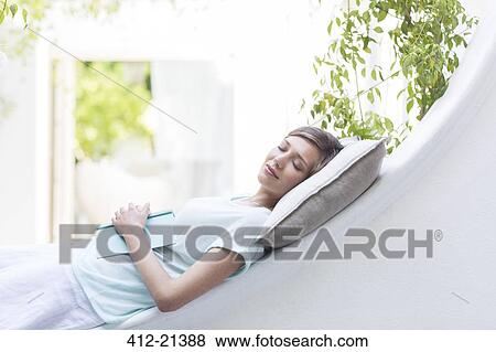 Stock Photo - Woman relaxing on pillow outdoors. Fotosearch