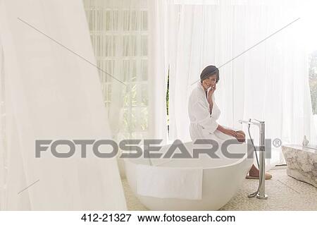 Woman running bath in modern bathroom View Large Photo Image Stock Photo - Woman running bath in modern bathroom. Fotosearch