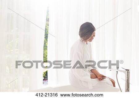 Woman running bath in modern bathroom View Large Photo Image Stock Photograph - Woman running bath in modern bathroom. Fotosearch