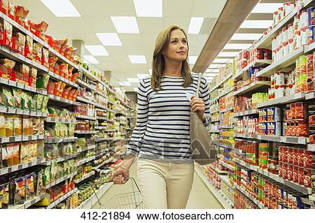 Woman shopping in grocery store aisle View Large Photo Image Picture - Woman shopping in grocery store aisle. Fotosearch