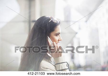 Woman talking on cell phone on city street View Large Photo Image Stock Image - Woman talking on cell phone on city street. Fotosearch