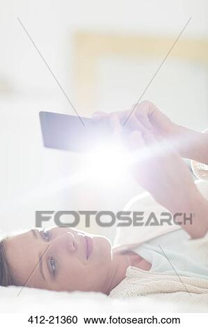 Woman using cell phone on bed View Large Photo Image Stock Image - Woman using cell phone on bed. Fotosearch
