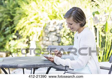 Woman using digital tablet at table outdoors View Large Photo Image Stock Image - Woman using digital tablet at table outdoors. Fotosearch