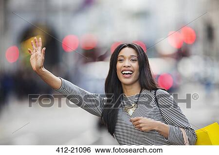 Woman waving for taxi on city street View Large Photo Image Stock Photograph - Woman waving for taxi on city street. Fotosearch