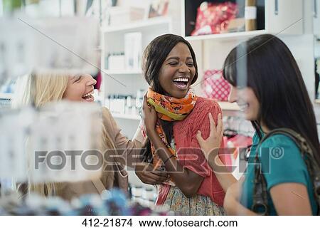 Women laughing together in clothing store View Large Photo Image Picture - Women laughing together in clothing store. Fotosearch