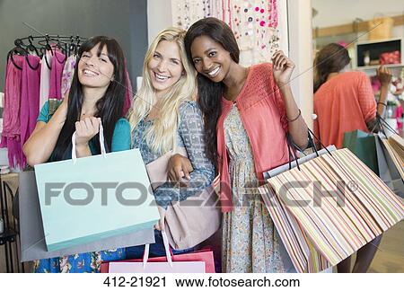 Stock Image - Women shopping together in clothing store. Fotosearch