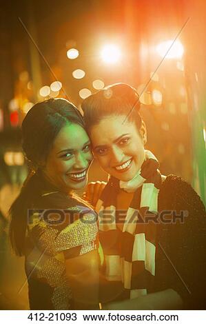 Women smiling together on city street at night View Large Photo Image Stock Image - Women smiling together on city street at night. Fotosearch