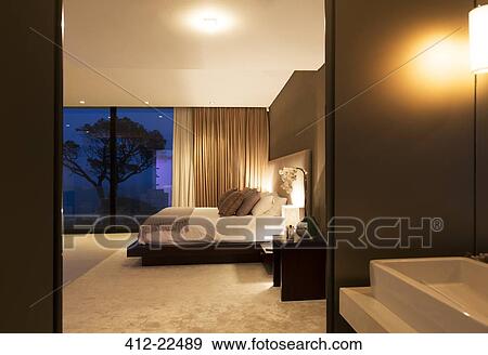 Beige and white bedroom with double bed seen from bathroom at night View Large Photo Image Stock Photo - Beige and white bedroom with double bed seen from bathroom at night. Fotosearch