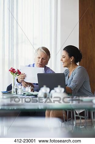 Stock Image - Business people discussing document in restaurant. Fotosearch