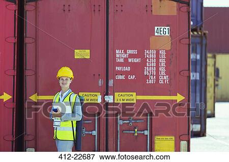 Stock Photo - Businesswoman smiling near cargo containers. Fotosearch