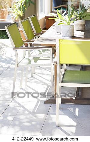 Stock Photo - Chairs and table with potted plants on patio. Fotosearch
