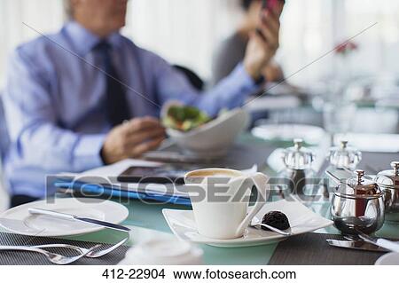 Close up of coffee cup on restaurant table, man in background View Large Photo Image Picture - Close up of coffee cup on restaurant table, man in background. Fotosearch