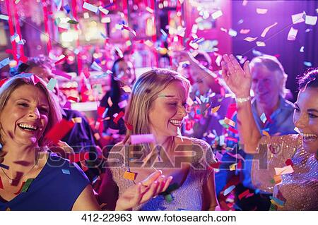 Confetti falling on smiling mature women dancing in nightclub View Large Photo Image Stock Image - Confetti falling on smiling mature women dancing in nightclub. Fotosearch