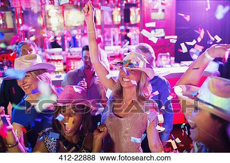 Confetti falling on women wearing cowboy hats dancing in nightclub View Large Photo Image Stock Photo - Confetti falling on women wearing cowboy hats dancing in nightclub. Fotosearch